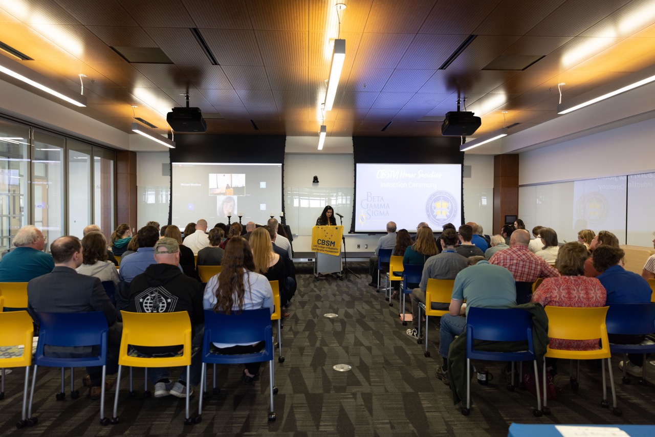 shot from the back of a conference of students seated listening to speech