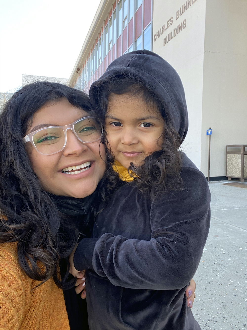 mother holds daughter while taking a selfie on a campus