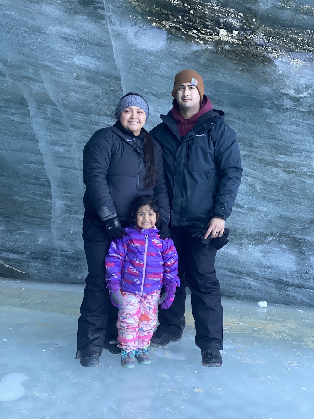mom, dad, and daughter wear winter gear at Castner Glacier in Alaska
