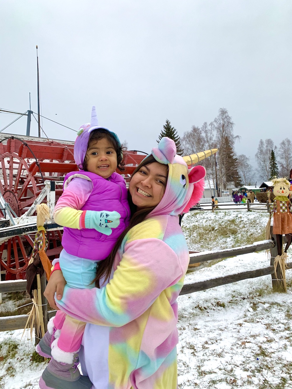 mother and daughter wear unicorn costumes outside on a snowy day