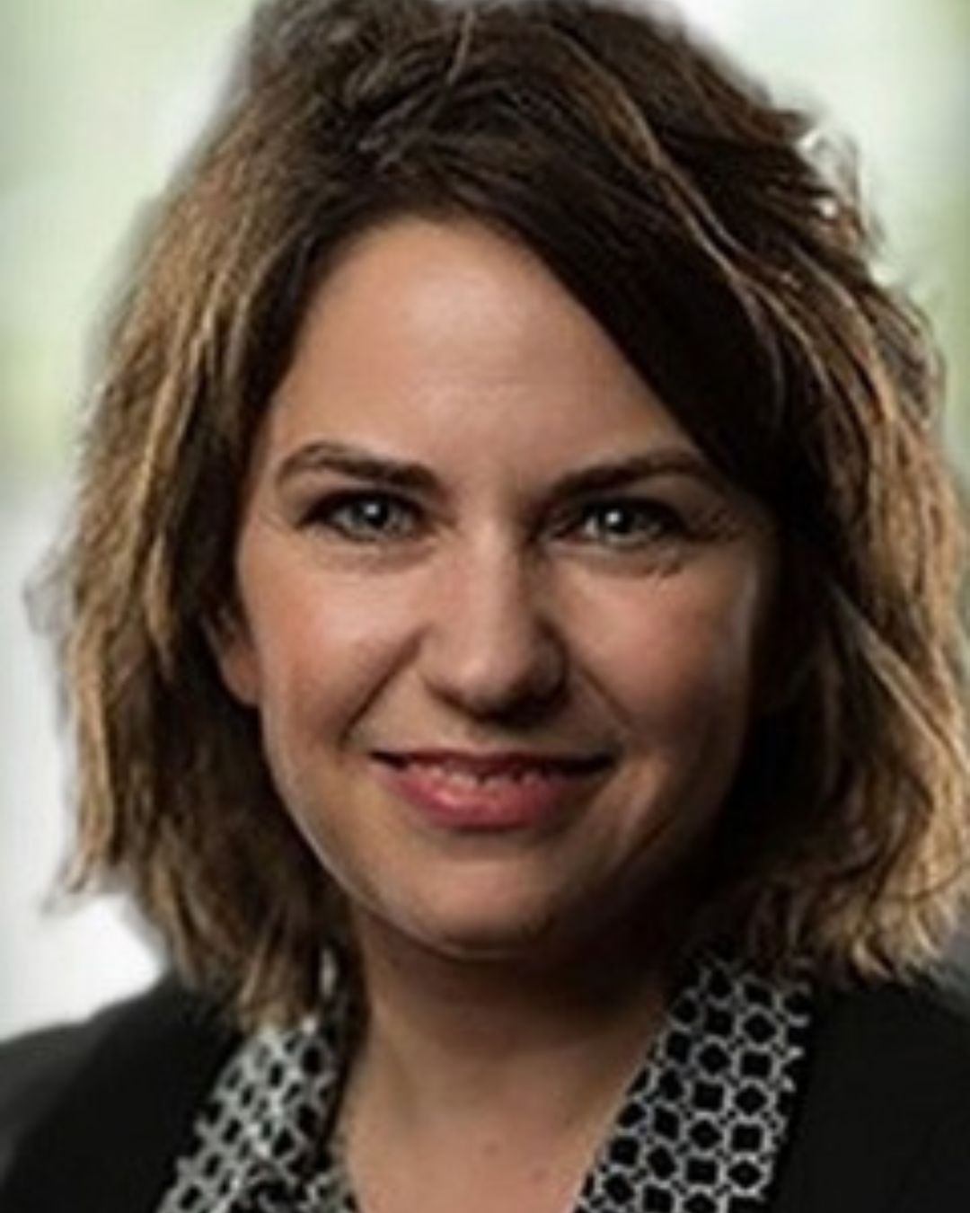 woman with short brown hair smiles for portrait with green background