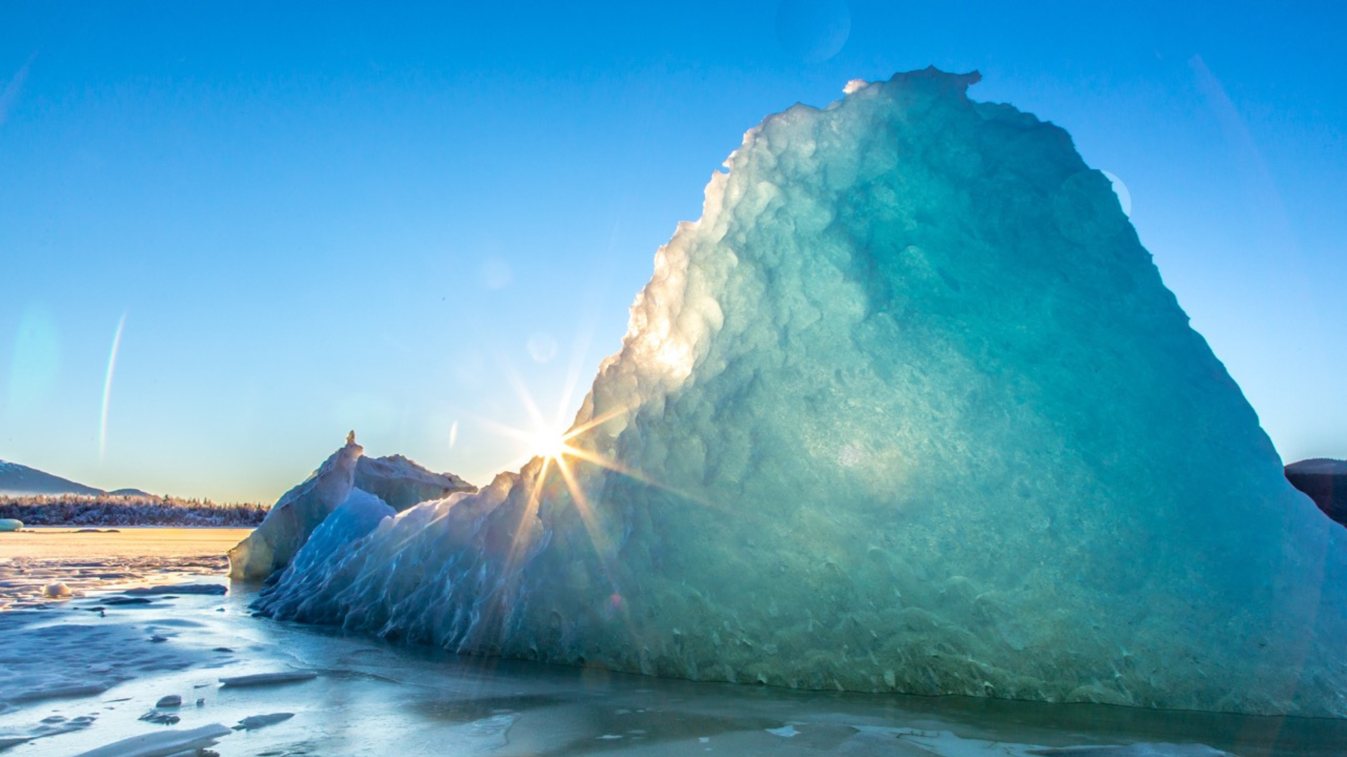 icy glacier gleams in the sun on the water