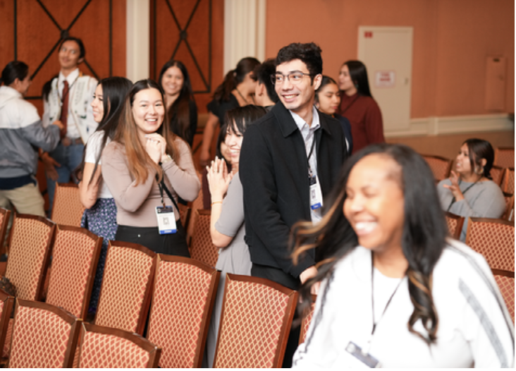 man and woman smile while leaving seats in auditorium