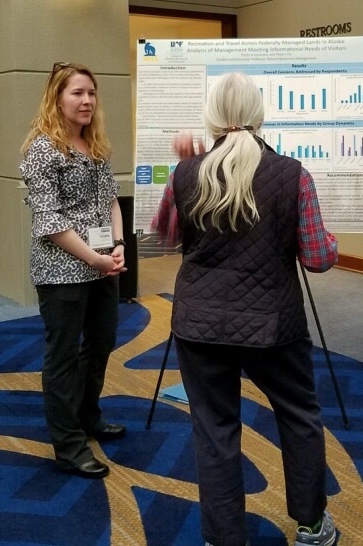 Trisha Levasseur, left, explains her visitor research poster to a conference attendee in Annapolis, Maryland.