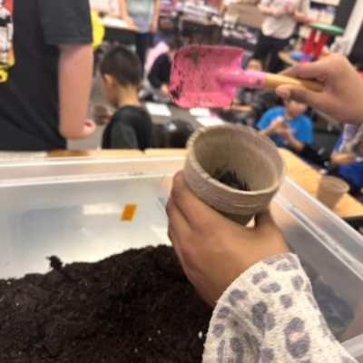 Child hands holding small flower pot and garden trowel