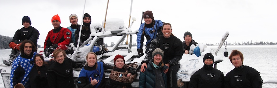 The dive class poses in their wet suits on a snowy boat and dock at the Kasitsna Bay Laboratory location