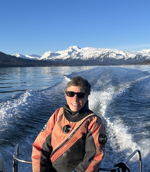 Brenda on the back of a boat in her diving suit