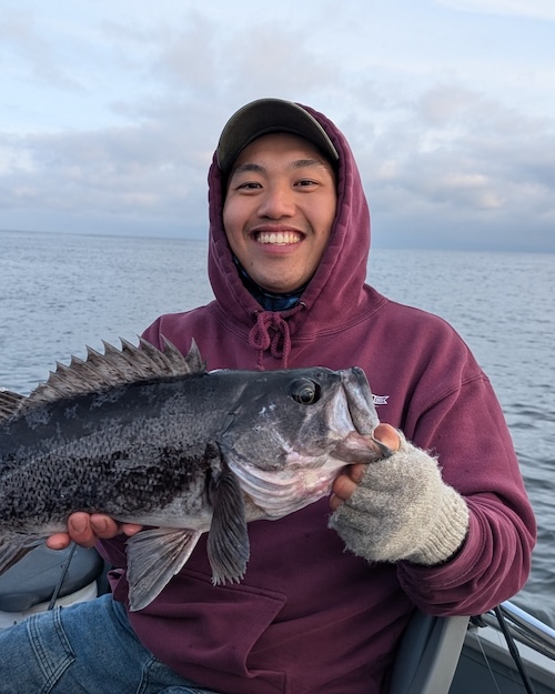 Andrew Chin holding a ling cod in a skiff