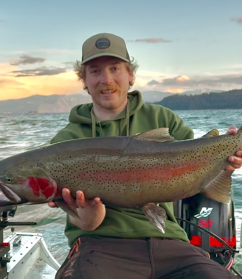 Tanner holds a salmon he just caught, while sitting in a skiff on the ocean