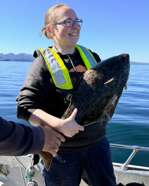 Danielle holding a halibut, smiling.