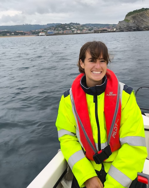 Neely Rylie sitting in a skiff on the water, smiling.
