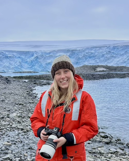Corrine Richard on a rocky beach in front of a glacier