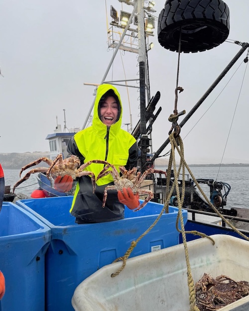 Teighan Shore Teighan onboard a ship holding crabs above a fish tote