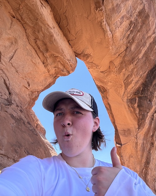 Photo of Kylie Wells under a blue sky with the orange rocks of the Grand Canyon around her