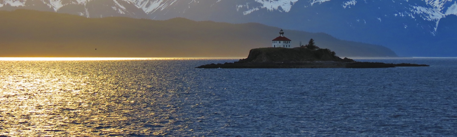 A lighthouse on an island at sunset