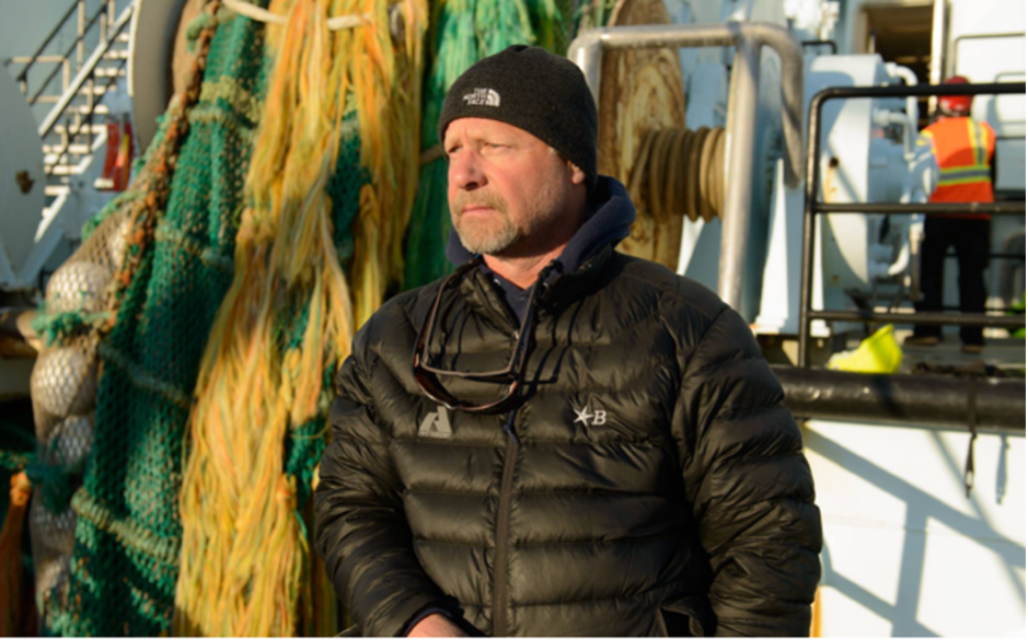 Photo of Karl Bratvold sitting on the deck of a trawl boat