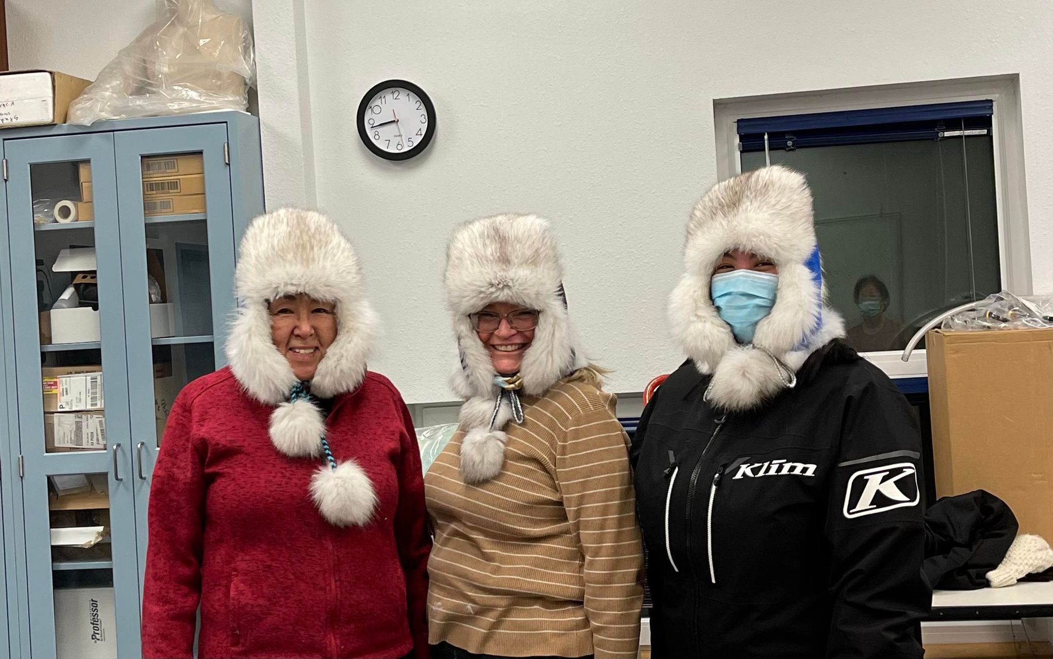 Three women pose wearing handmade beaver fur hats that almost obscure their faces.