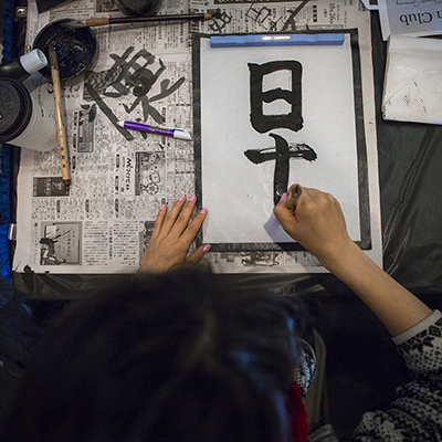 An overhead image of a student practicing kanji figures from the UAF We Are CLA event