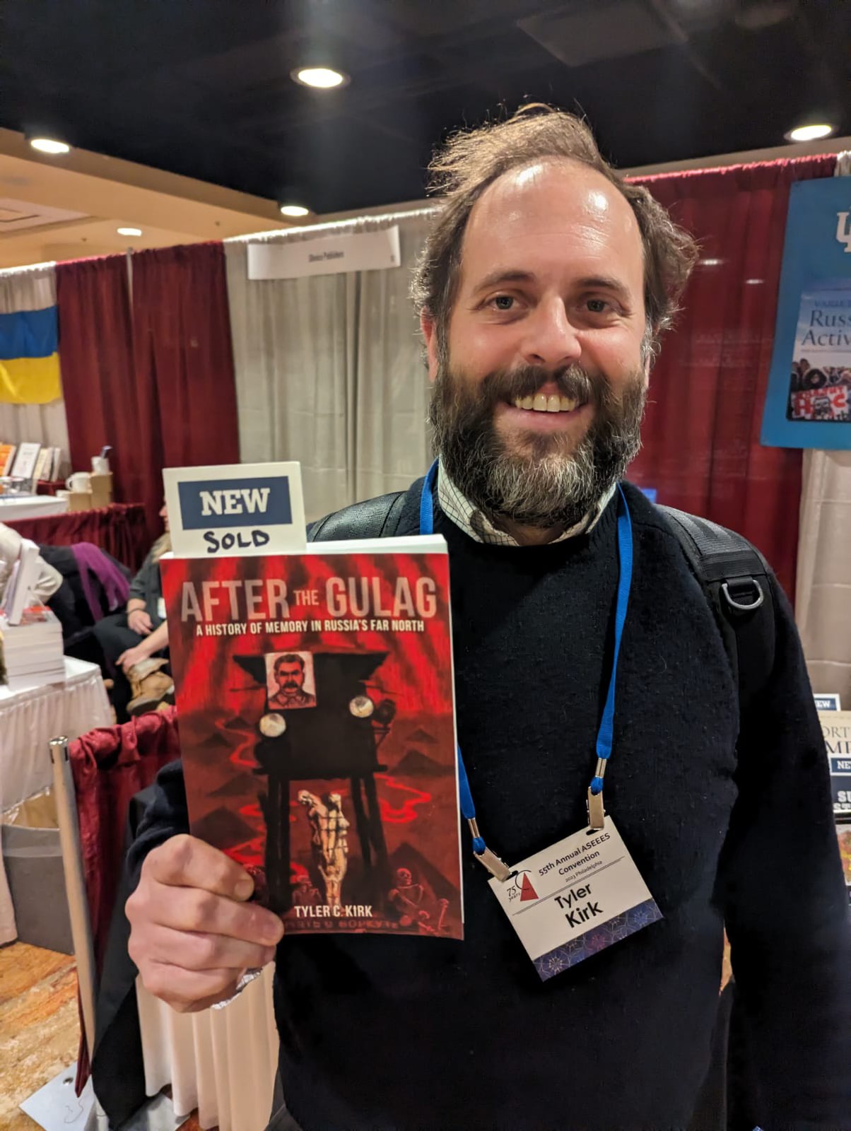 Dr. Tyler Kirk smiles while holding his newly released book, After the Gulag