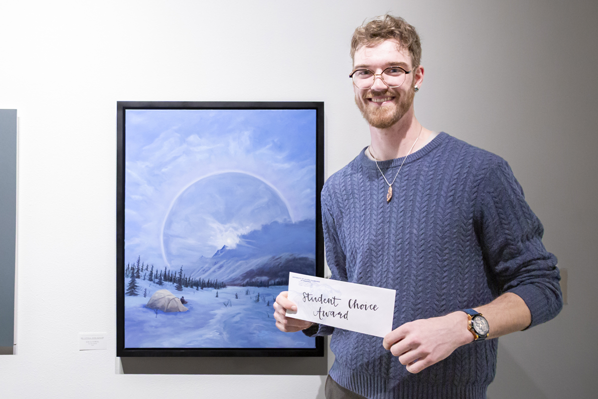 Fin Ludwig with his painting, Be Still and Know, which won the People's Choice award. UAF Photo by Sarah Manriquez