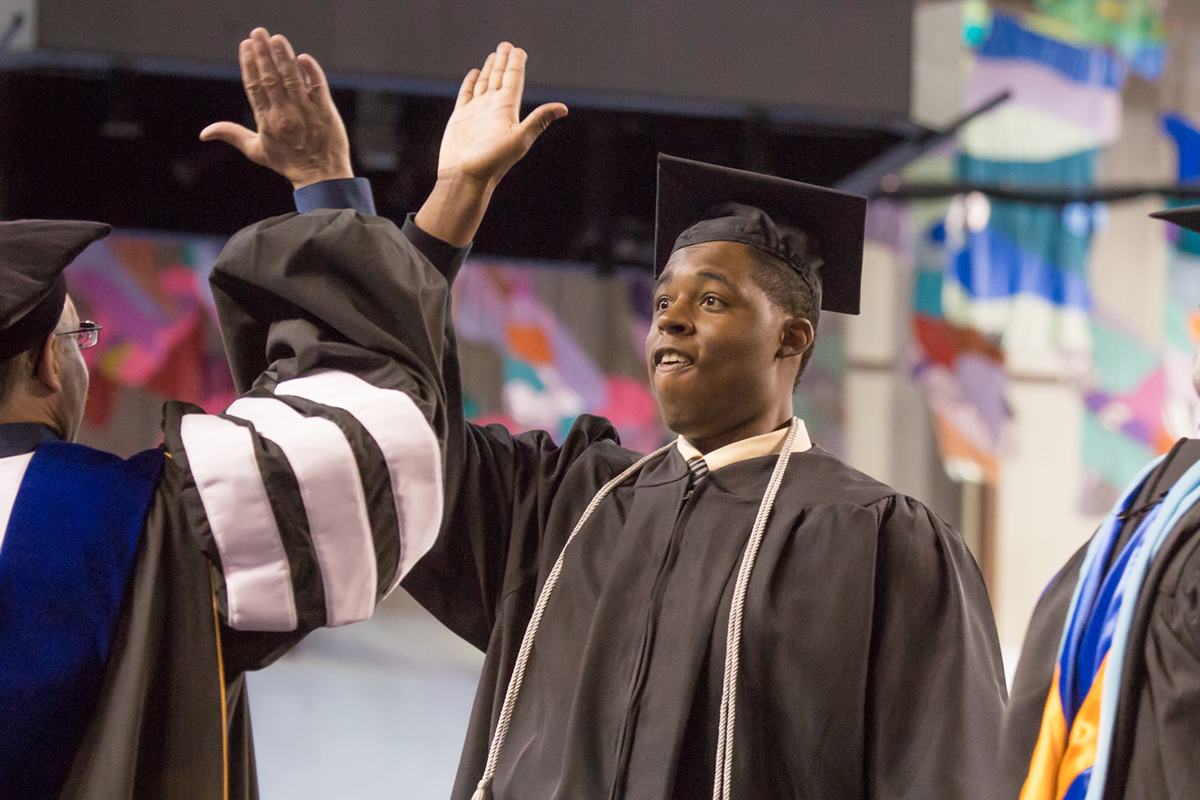 Robert Kinnard III shares a high five with Vice Chancellor Mike Sfraga after earning his degree in justice. UAF Photo by Todd Paris