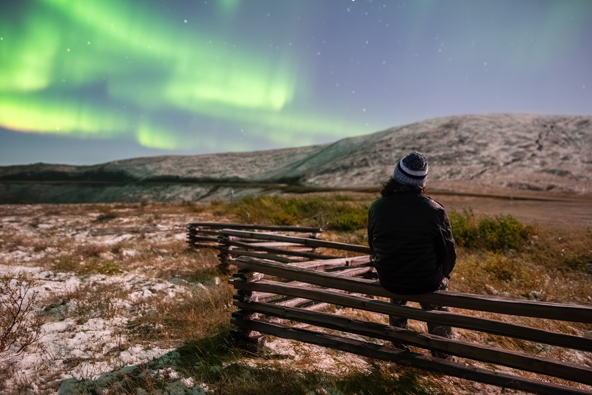 Andy Witteman sitting on a fence watching the aurora. Photo courtesy of Witteman