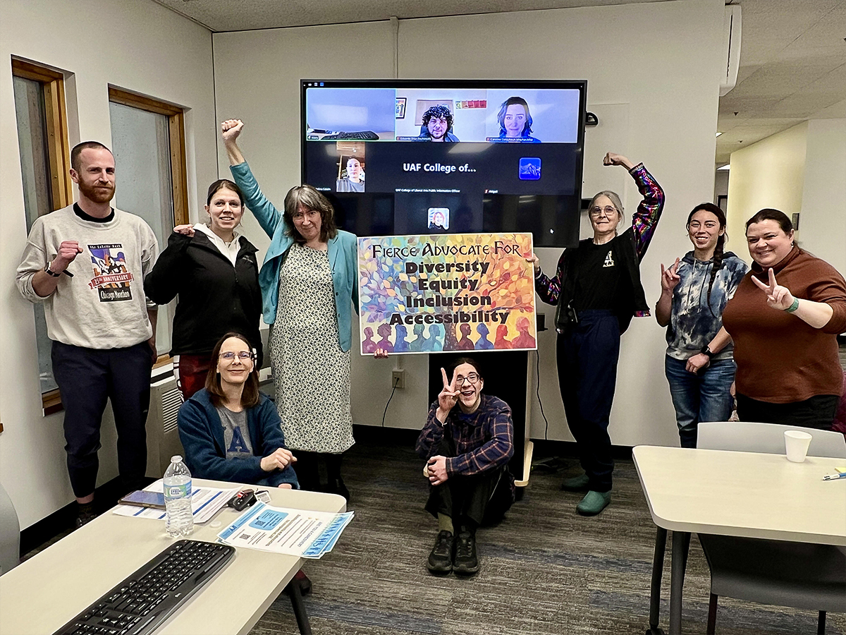 WGSS faculty and staff pose by a DEI sign at the end of a weekly meeting. UAF Photo by Jamie Bennett