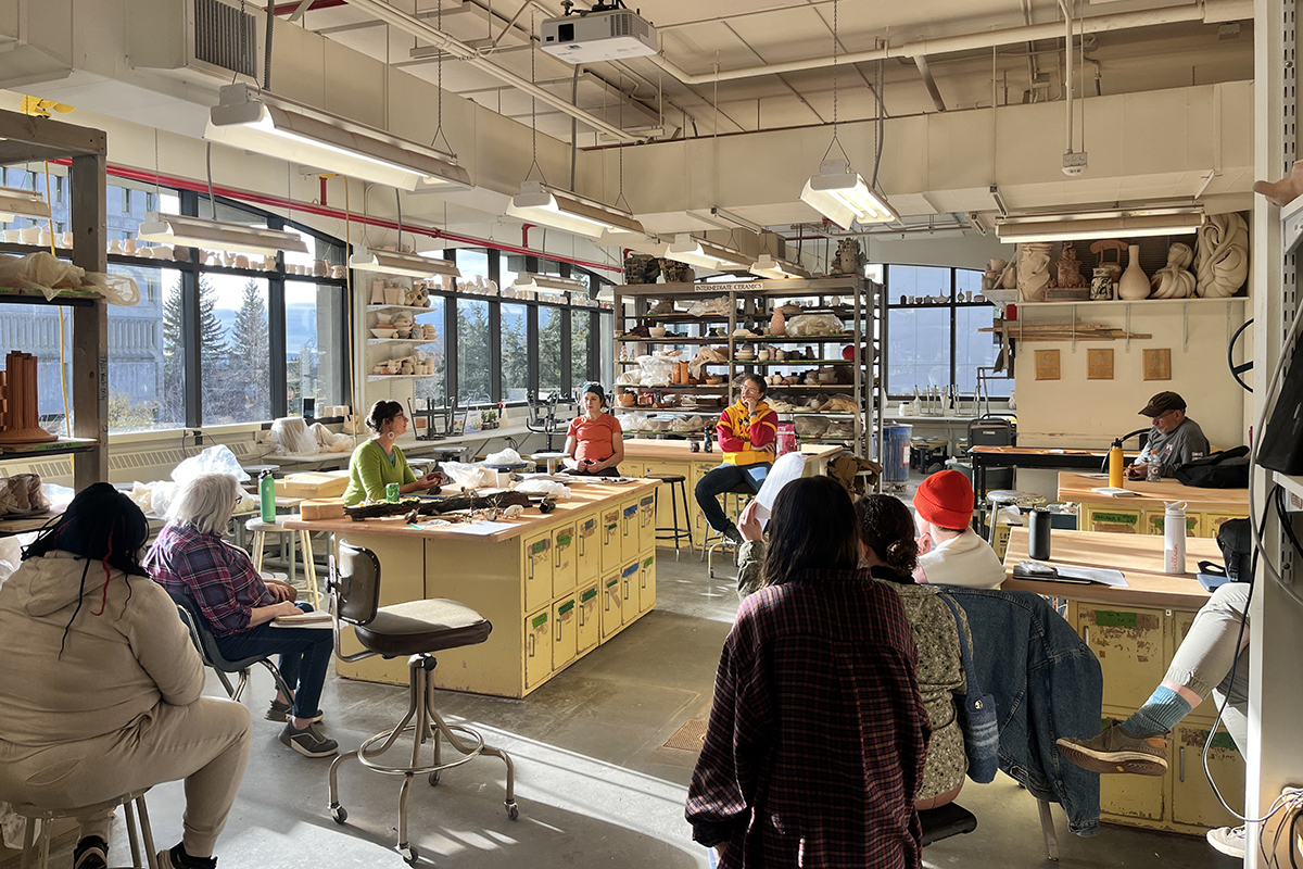 Gathered around the studio tables, participants listen as visiting artist Dawn Holder shares her process and approach to making. UAF Photo by Abby Druckenmiller
