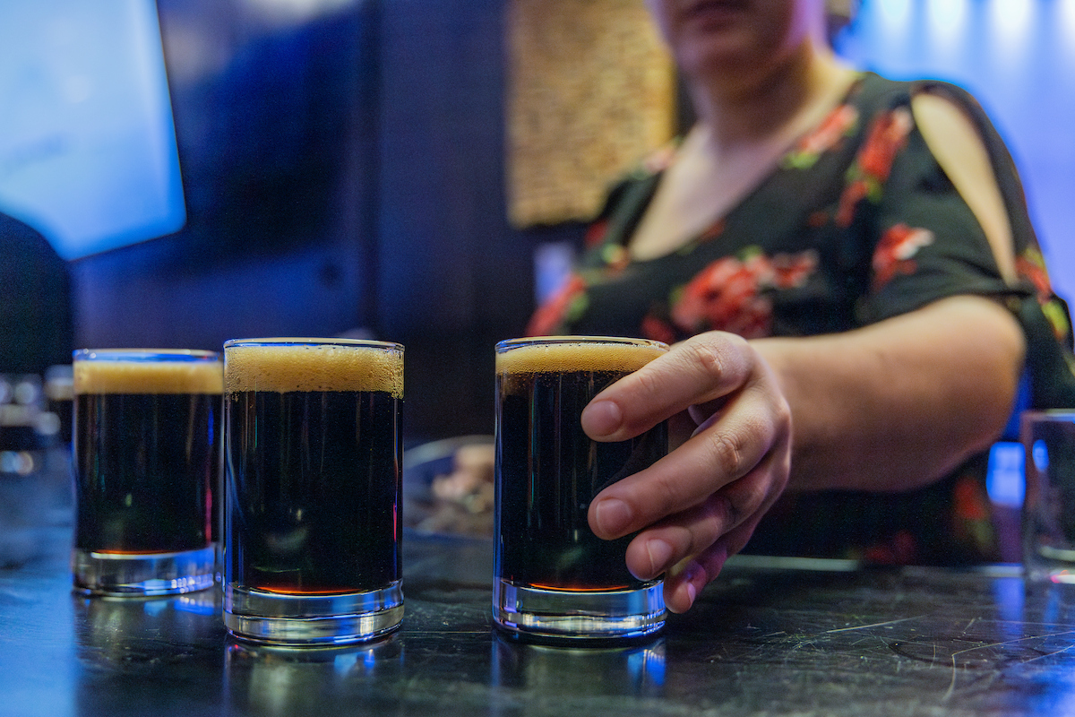 A bartender at the UAF Pub lines of three glasses of beer on the bar top. UAF Photo by Marina Barbosa Santos