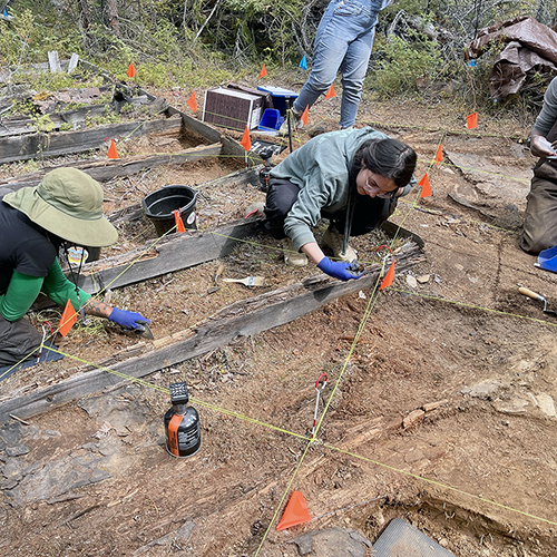 Alaska Highway Archaeological Field School students (Left to right T. Watson-Glen; Amilia Galdiano; Sean Adams) excavating the southeast corner of an outhouse. Photo courtesy of MoHagani Magnetek, June 2025.