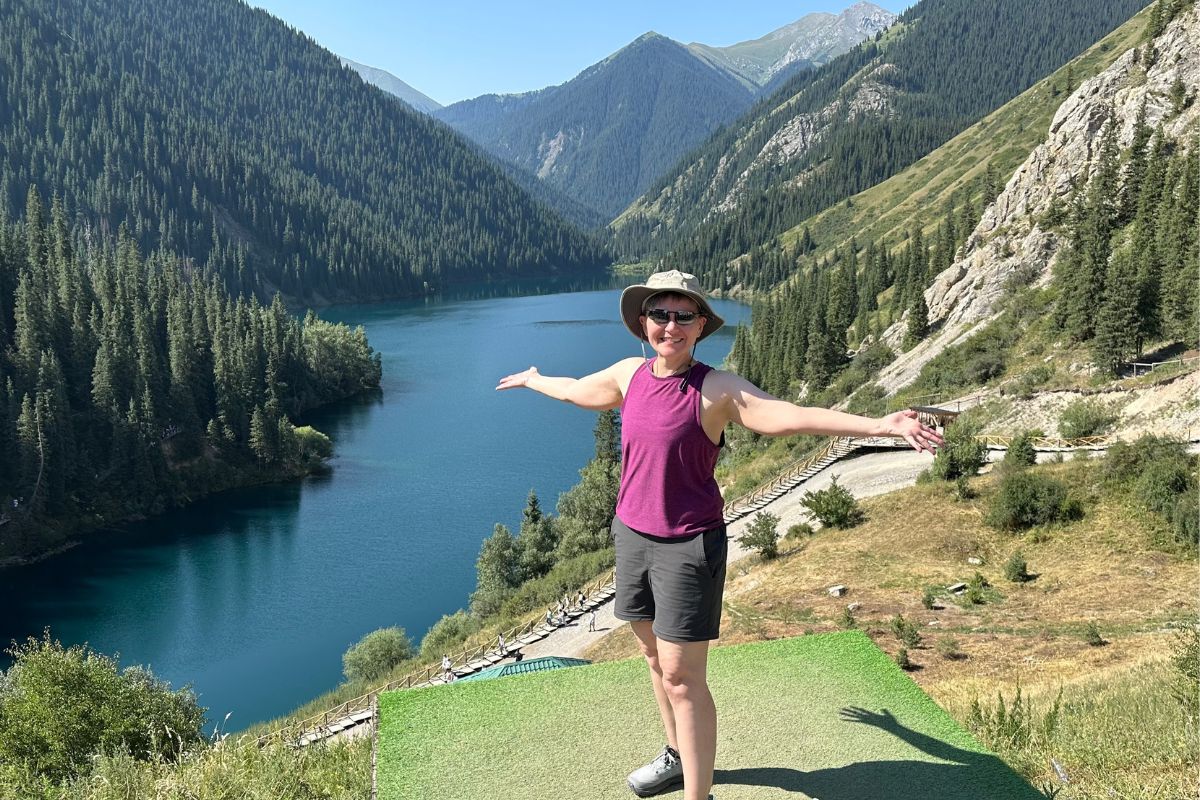 Wendy Martelle poses in front of a mountain and lake in Kazakhstan. Photo courtesy of Wendy Whitehead Martelle