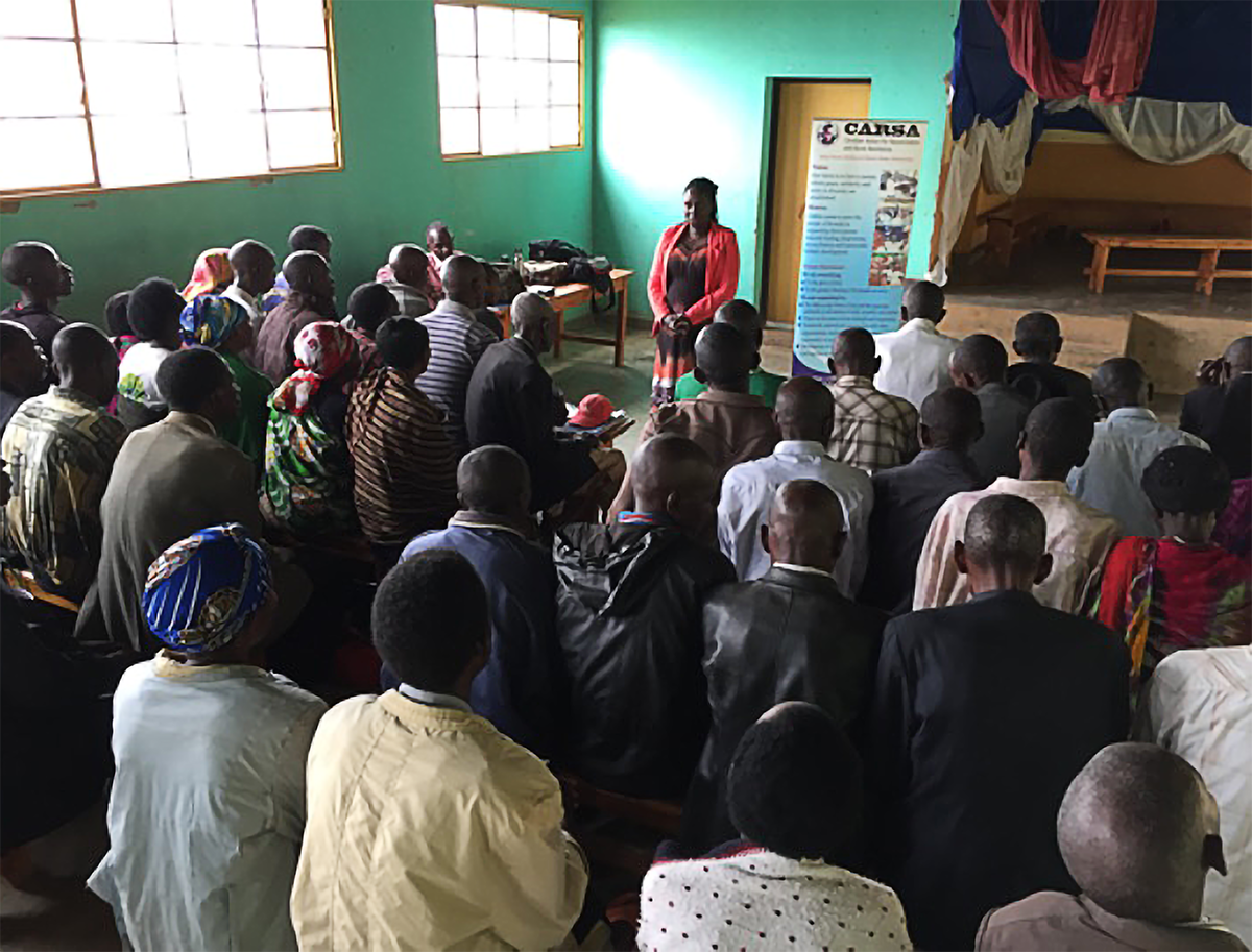 Group of community members seated in a room in Kigali listen as a facilitator leads a CARSA Peace Conversation Circle, focused on dialogue and reconciliation.