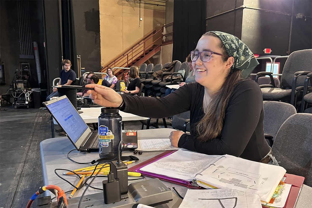 Zorissa James provides actors direction from a table during a theatre production rehearsal.
