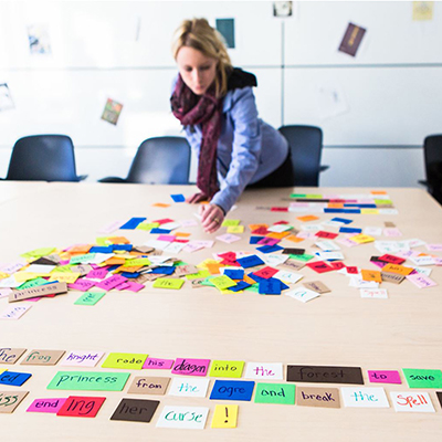 A participant in the Department of English's Celebration of Writing adjusts words written on post its on a table