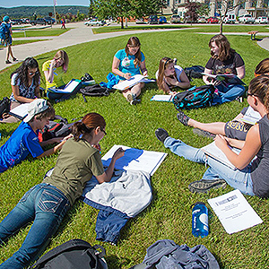Students sitting outside on the grass having class