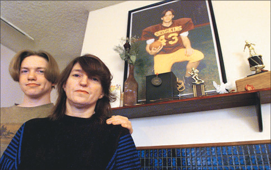 John Hartman’s mother, Evalyn Thomas, and his brother, Michael Kelly, are seen in front of a memorial in their home in October 1998, one year after the 15-year-old’s murder.