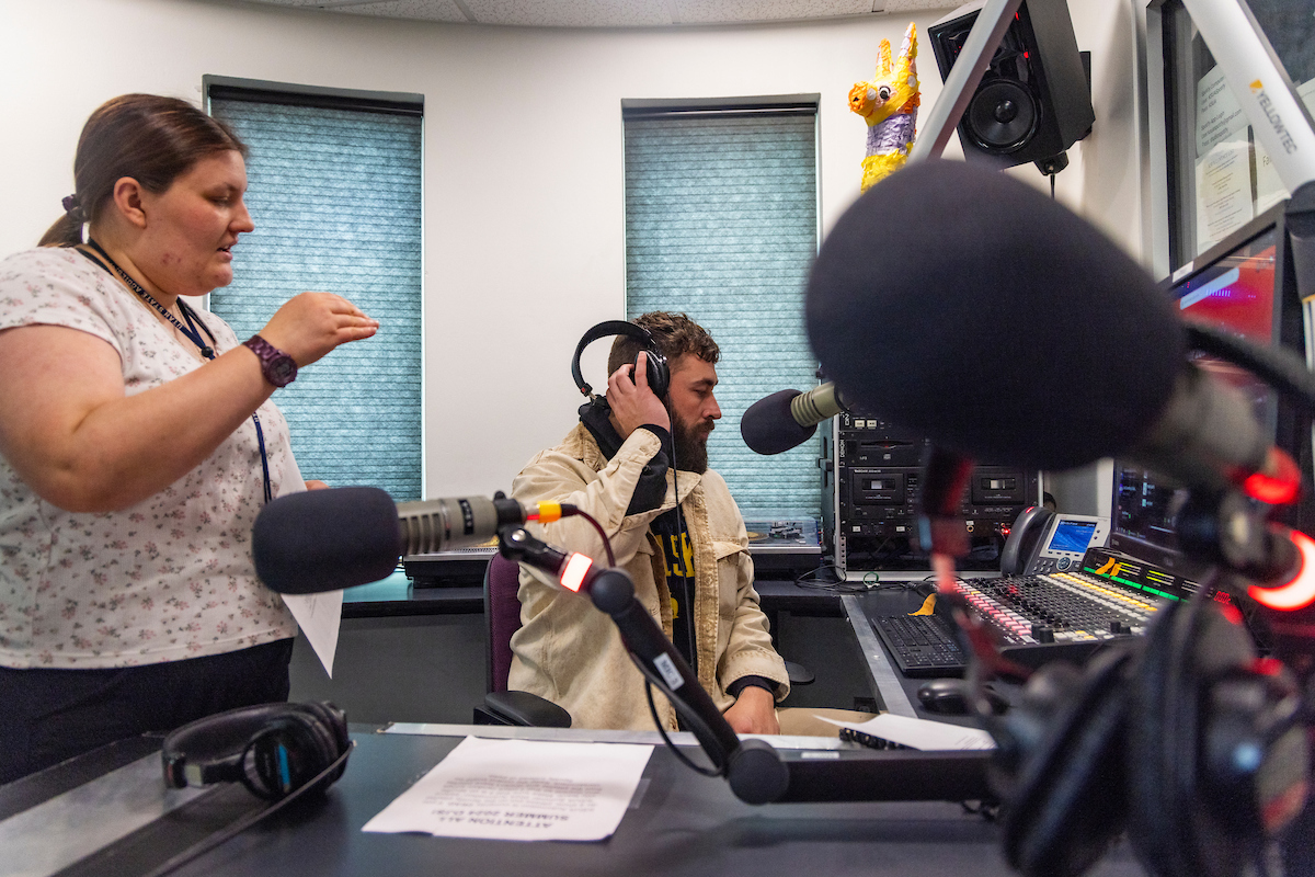 KSUA's Kjirsten Schindler trains new radio show host, Jake Knuth, on the various components of their studio  located on the second floor of the Wood Center, 7/29/24. (UAF photo by Leif Van Cise)