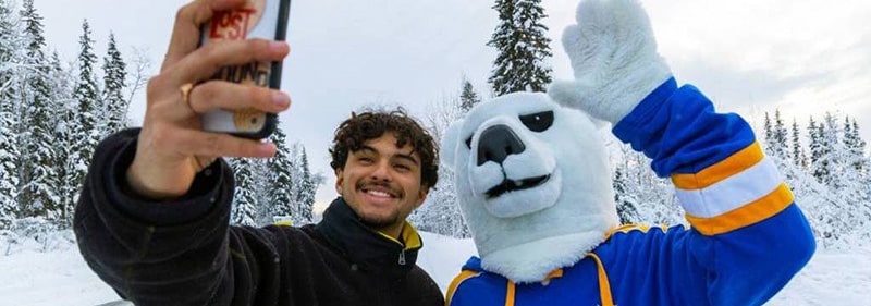 Student takes selfie with the UAF mascot Nook
