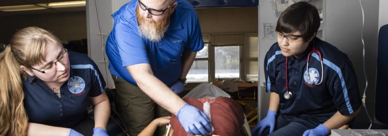 Paramedicine students look on as an instructor performs a demonstration