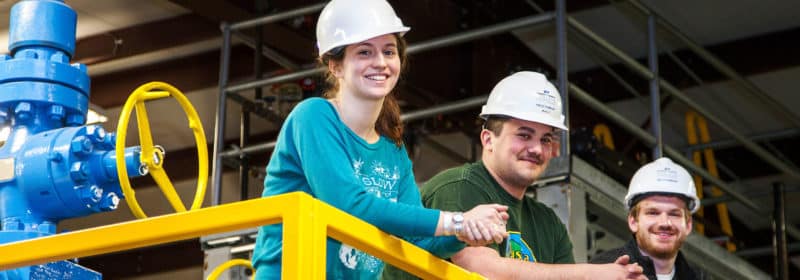 Three students wearing hard hats