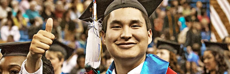 Student giving a thumbs up while graduating