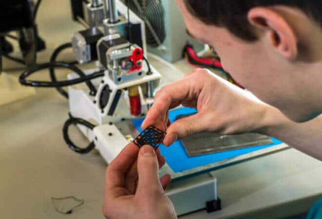 Stephen Ramirez inspects an item fabricated by a 3-D printer at the UAF Community and Technical College.