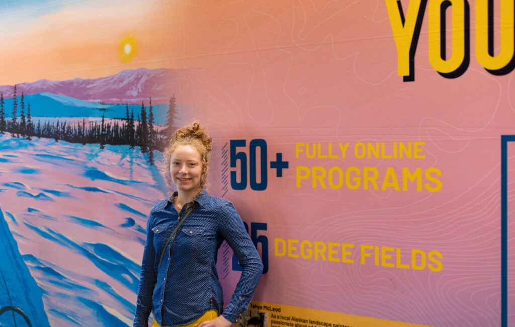 Tehya McLeod at SEATAC airport with CTL display using Tehya’s “On the Trail” artwork
