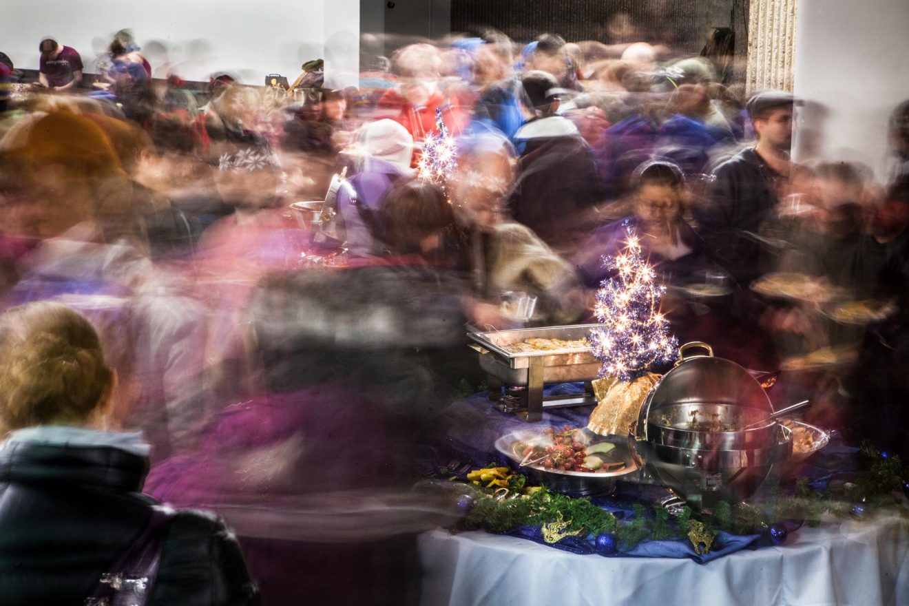 Busy crowd moving around a holiday buffet table.