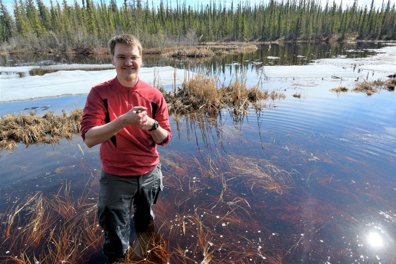 Don Larson stands in a pond with a frog.