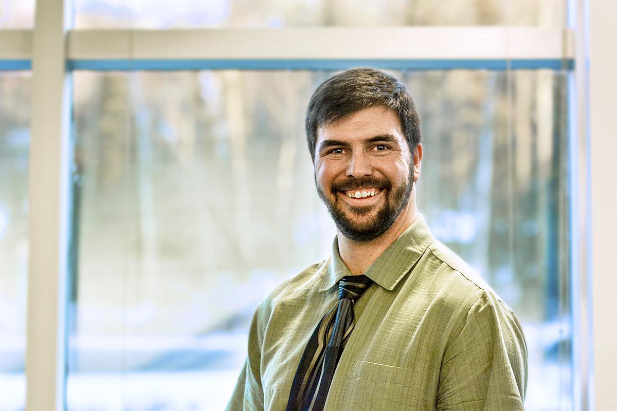 Brandon Briggs stands in a shirt and tie inside a building.