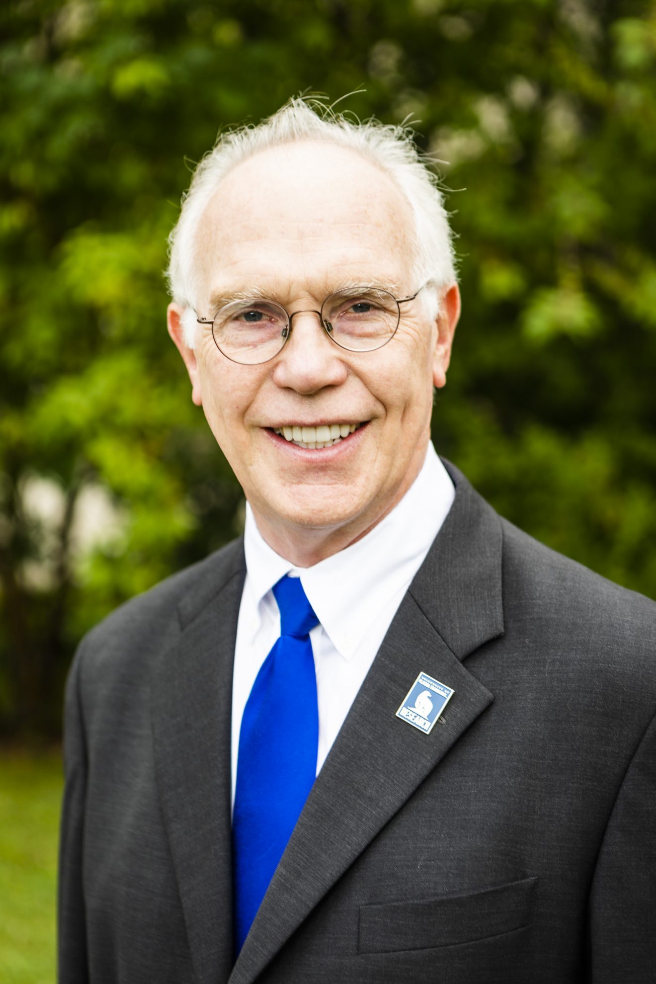 Head shot of Larry Hinzman in coat and tie, outside during the summer.