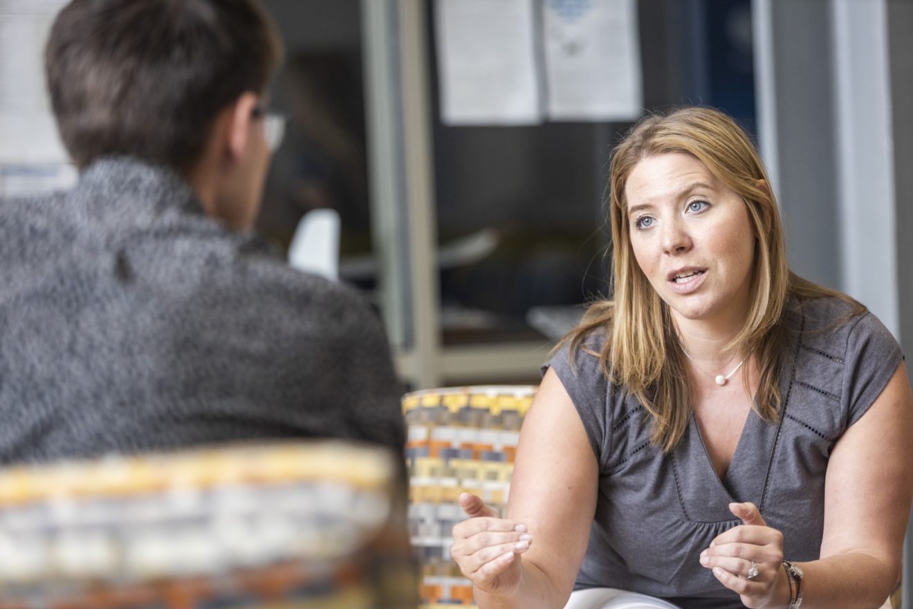 Julie Queen sits talking with an unidentifiable person