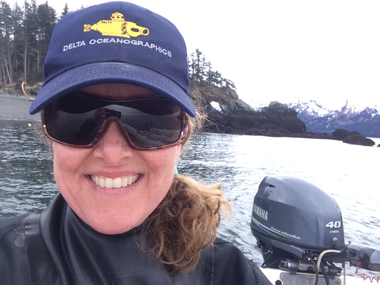 Head shot of Eloise Brown, standing with a boat engine behind her on the water in a coastal marine setting.