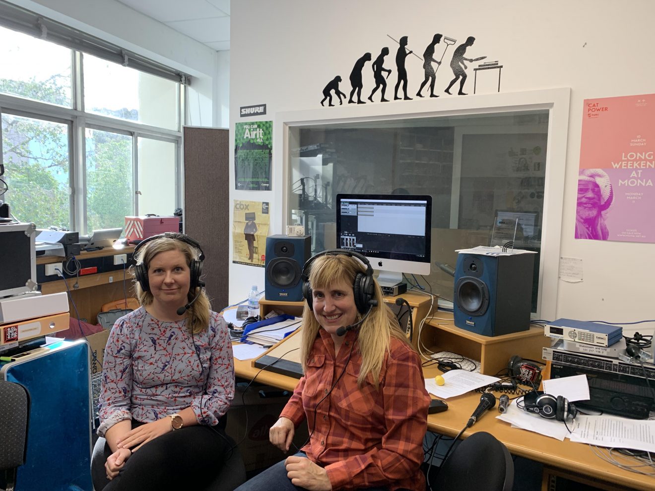 Two women sit in a radio studio. They are wearing headsets.